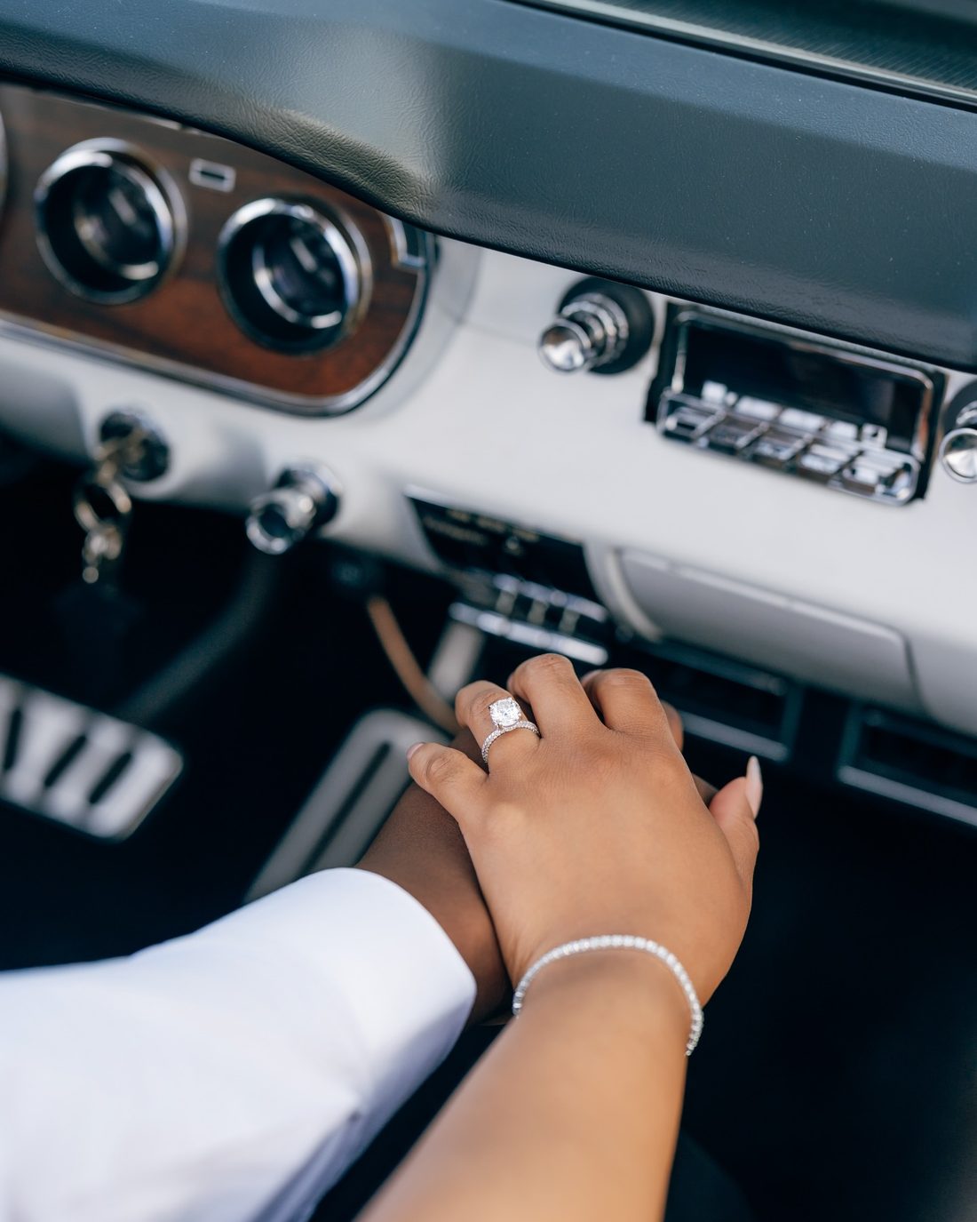 A couple's hands, and the ring, photographed in a vintage car