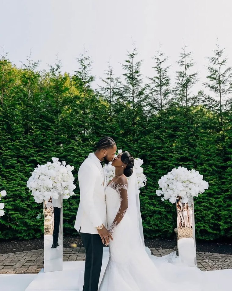A couple kissing between two tall floral pedestals