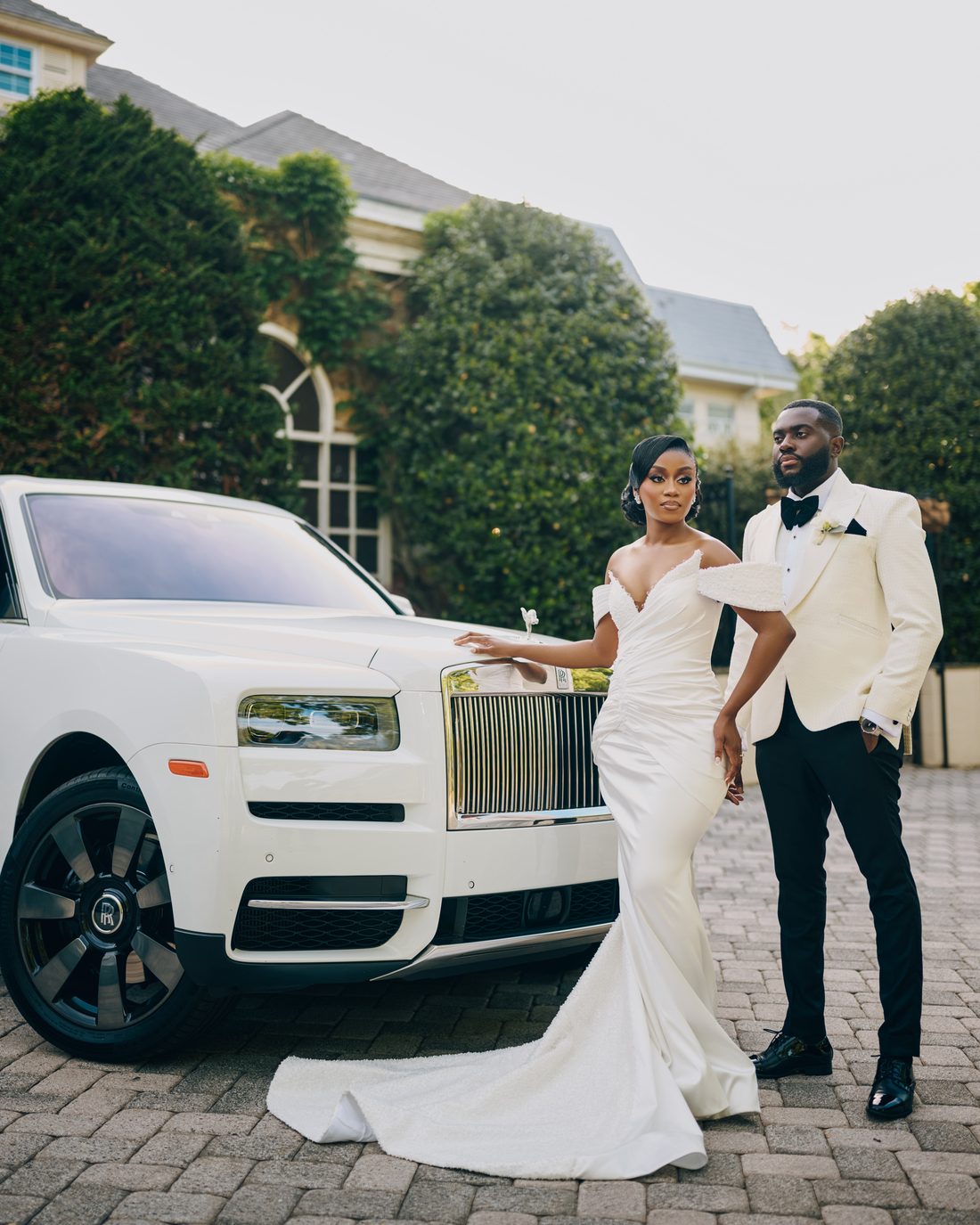 A couple arriving at their venue beside a white car
